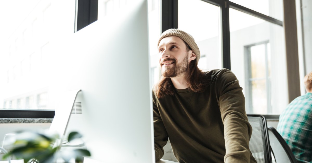 Mann sitzt im Büro an einem großen Bildschirm und schaut zur Seite