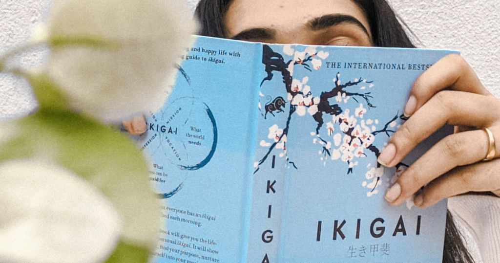 Frau haelt das Buch IKIGAI von Hector Garcia und Francesc Miralles vor ihr Gesicht